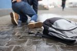 Man with backpack felling on slippery sidewalk in winter closeup. Ice injuries concept