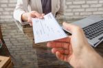 Close-up Of A Business Woman Giving Cheque To Her Colleague At Workplace In Office concept